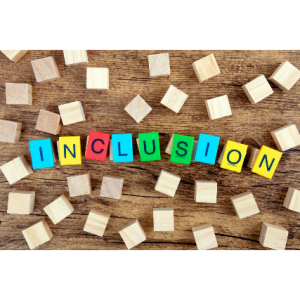 Colorful letter blocks spelling 'Inclusion' on a wooden surface with scattered wooden cubes